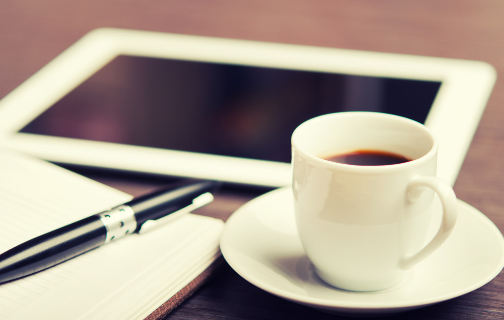 workplace, office desk: coffee and tablet pc and notebook with p